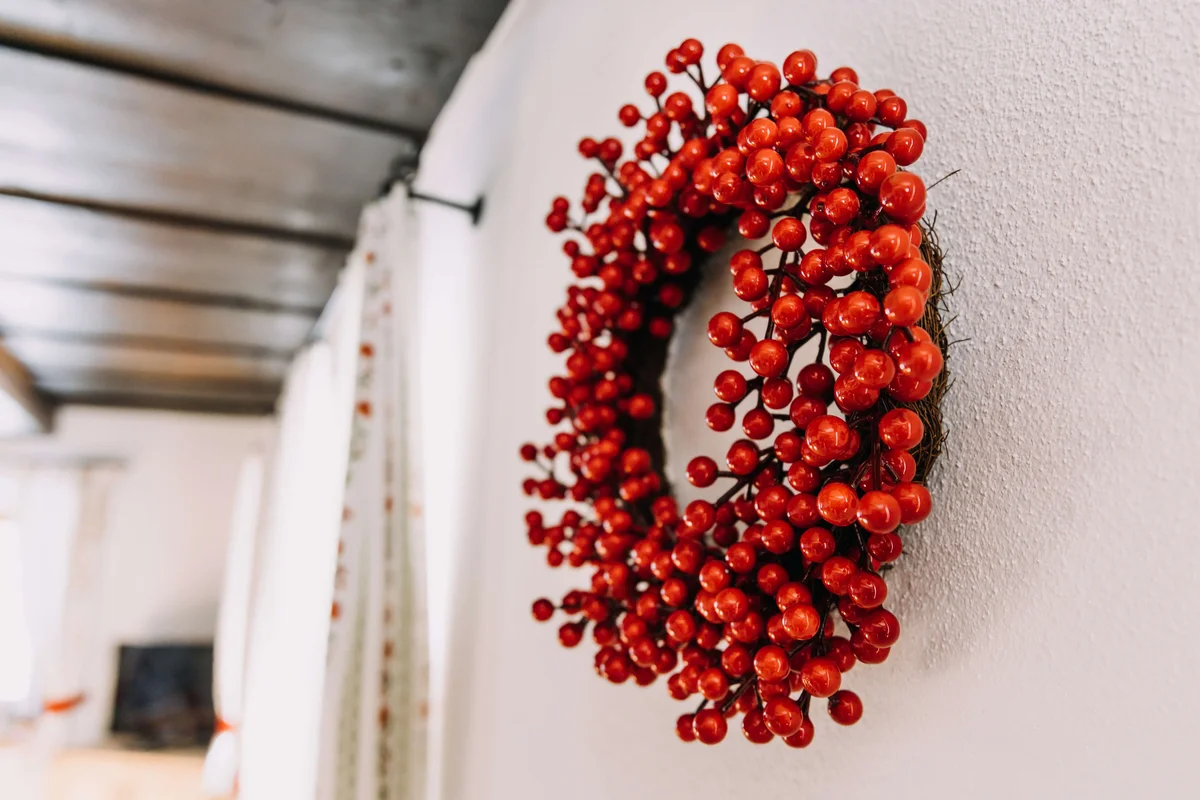 Dekorativer Kranz mit roten Beeren an der Wand im alpinen Stil
