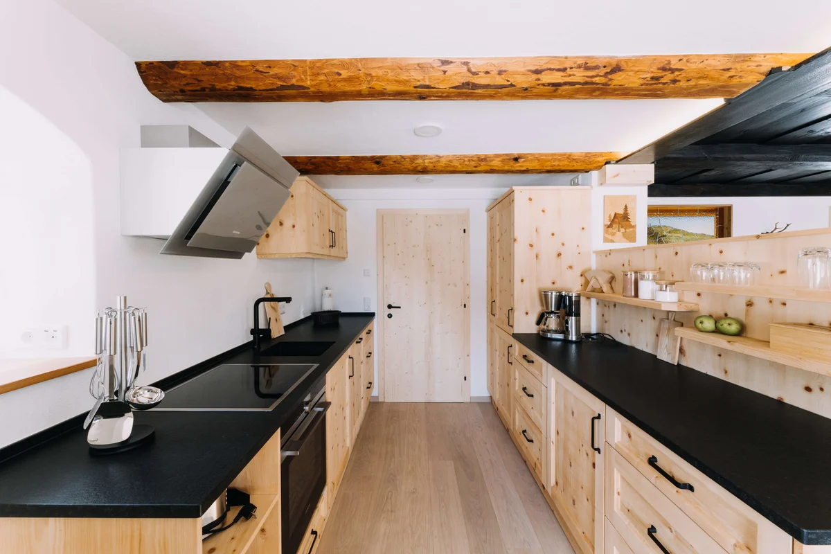 Moderne Küche mit Holzfronten und schwarzen Arbeitsflächen in der Unterkunft