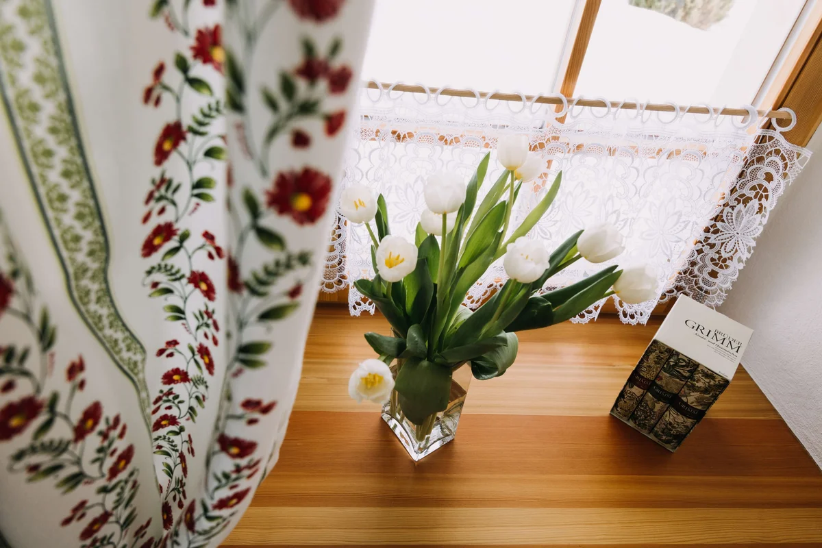 Detailaufnahme mit Blumen und dekorativen Vorhängen im Landhausstil