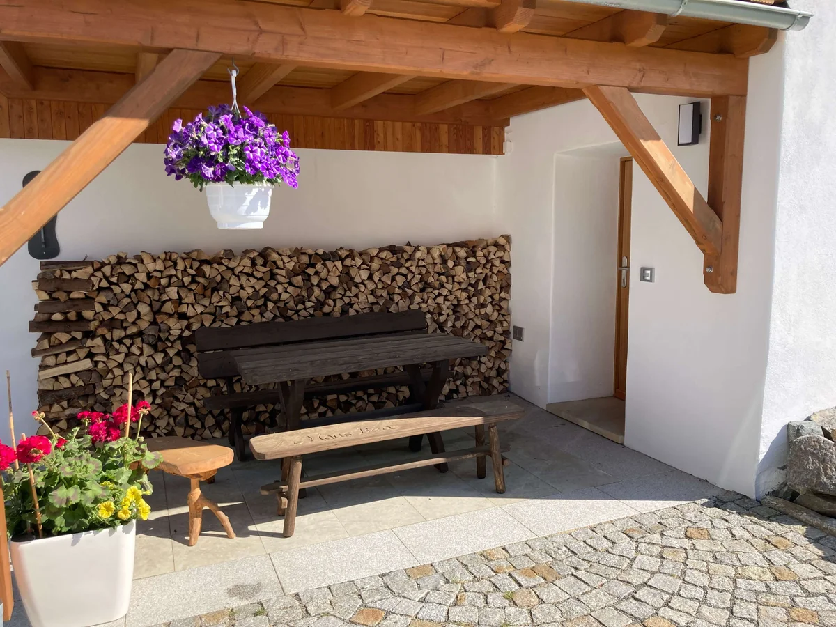 Überdachte Terrasse mit Sitzbank und Holzlager im Außenbereich